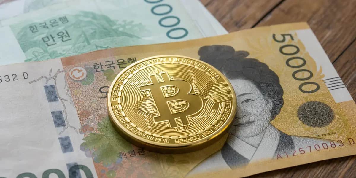 원화 지폐 위에 놓인 비트코인 모양의 금색 동전을 얕은 심도로 근접 촬영한 사진으로, 가상자산 소득 과세 시행일이 2027년에서 2030년으로 유예되는 법안 발의 소식을 상징적으로 보여준다
