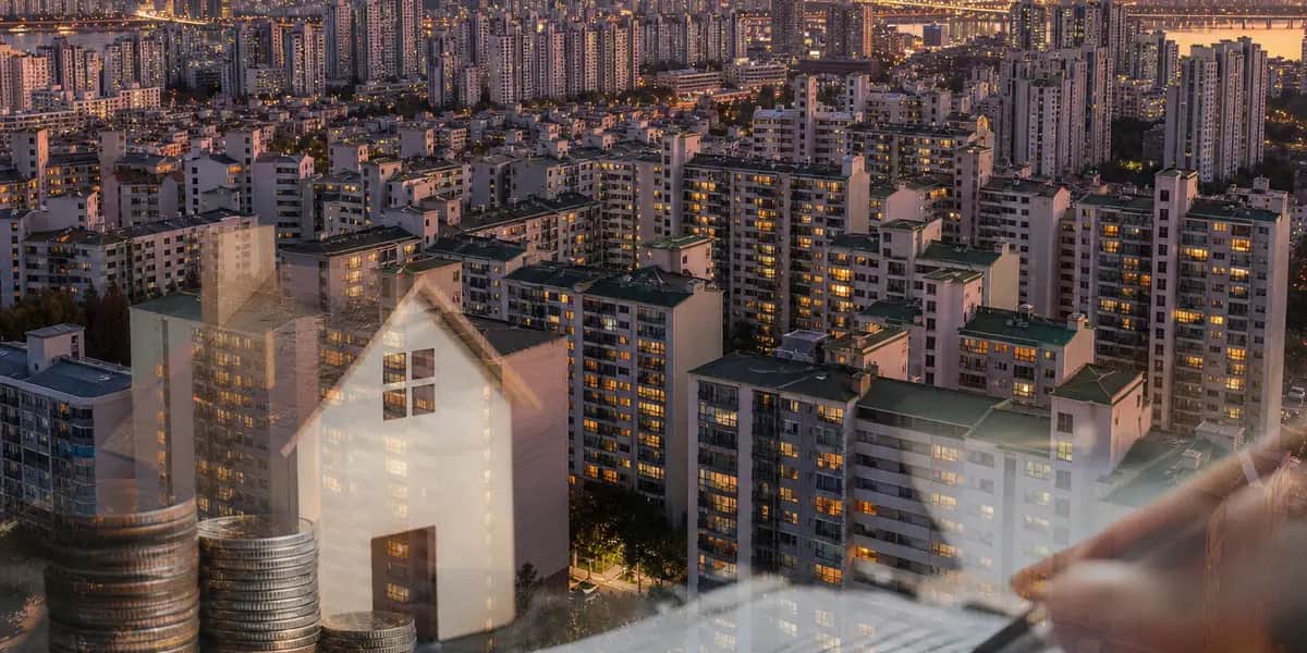 노을 무렵 낮은 고도에서 바라본 한국 도시의 초고층 아파트 단지 모습으로, 가로세로로 빽빽하게 들어선 주거 빌딩들의 창문에 불이 하나둘 켜지고 있어 부동산 보유 세제 변화를 상기시키는 밀집 주택 항공 전경 사진